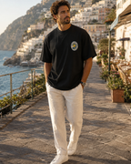 Man wearing black Amalfi Road Club T-shirt with small front logo in Positano Italy