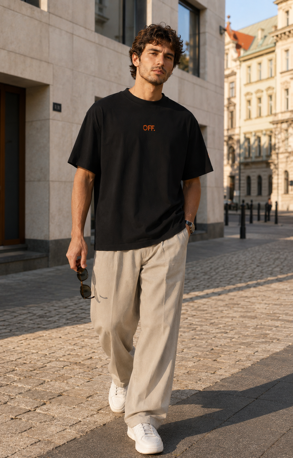 Young man wearing a black oversized organic cotton T-shirt with orange OFF embroidery.