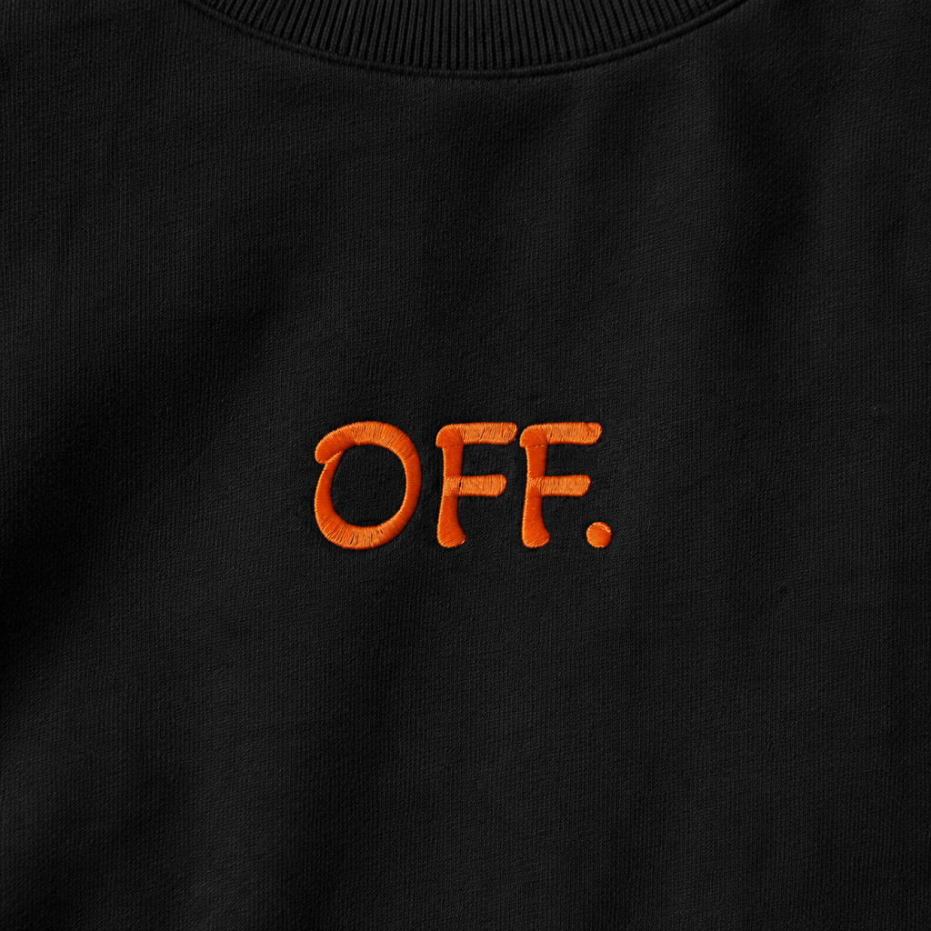 Close-up of orange OFF embroidery on a black oversized organic cotton T-shirt.