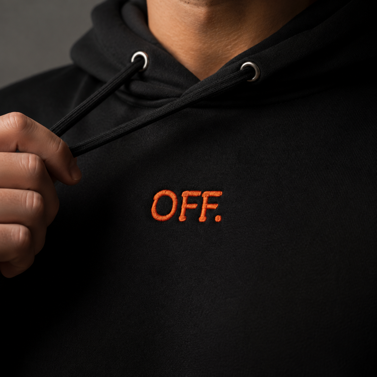 Close-up of orange OFF embroidery on a black organic cotton hoodie