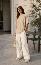 Young woman wearing a stone oversized organic cotton T-shirt with orange OFF embroidery.